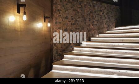 Illuminated staircase with wooden steps and illuminated at night in the interior of a large house. Stock Photo