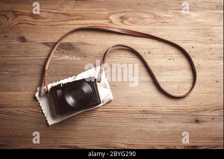 vintage style of digital mirrorless camera with leather strap isolated on wooden background Stock Photo