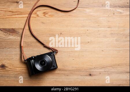 vintage style of digital mirrorless camera with leather strap isolated on wooden background Stock Photo