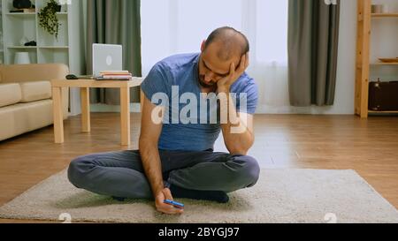 Pensive man using his phone during covid-19 self isolation. Stock Photo
