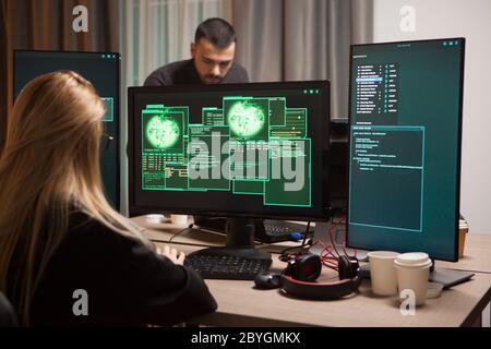 Blonde female hacker stealing secret information. Team on cyber criminals. Stock Photo