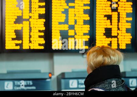 Young woman looking at the information board trip, checking her destiny, rear view Stock Photo