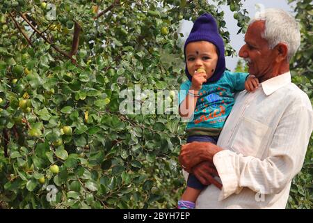 March 6, 2020. happy child and mid age grand father standing in the garden rajasthan, india Stock Photo