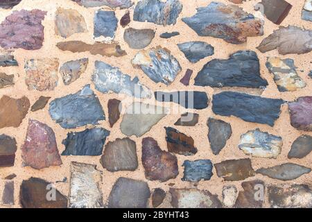 Stone wall background, building feature. Texture of thick and strong wall of rough stones of various shapes and sizes Stock Photo