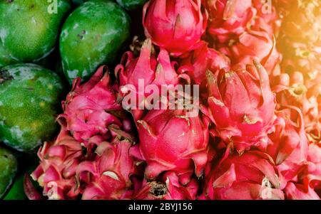 Full frame close-up shot of two different variety of fruits, green mangoes and pinkish red Dragon fruit. Copy space for text. Stock Photo