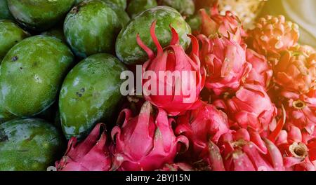 Full frame close-up shot of two different variety of fruits, green mangoes and pinkish red Dragon fruit. Copy space for text. Stock Photo