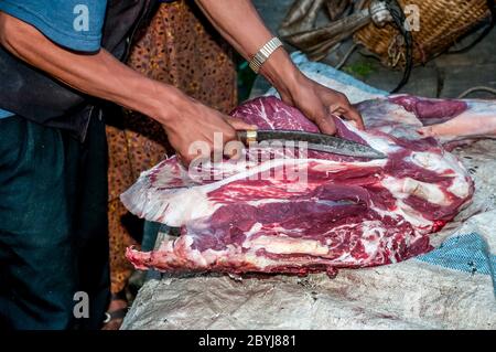 Nepal. Island Peak Trek. A visiting butcher demonstrates his skills to waiting Sherpa lady customers. Meat is a real treat for families in what is a basic vegetarian diet. The butcher has carried two whole leg loins of a Jak cow along the the animals liver from Lukla town several hours walk away visiting  all the small communities until there is nothing left of the meat. Even the bones will be used to make soup-broth then later pounded to dust to provide fertiliser Stock Photo