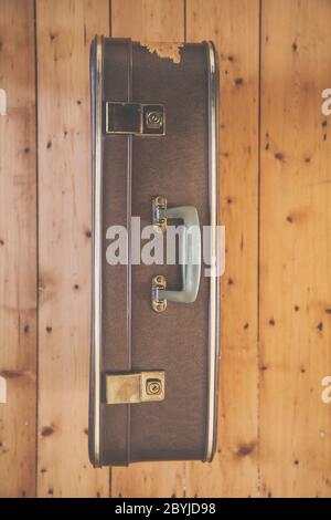An old vintage brown travel suitcase on a wooden floor Stock Photo