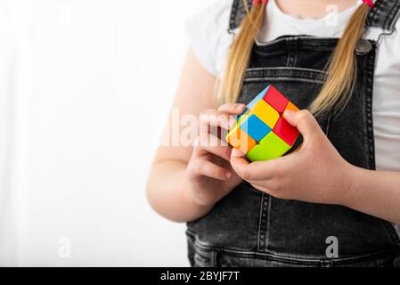 Minsk, Belarus, June 9, 2020: Rubik's cube in the hands of a little girl. A child holds a Rubik's cube on a light background, playing with it Stock Photo