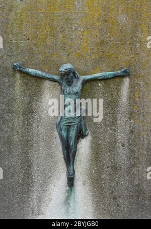 iron effigy of Jesus Christ against a concrete stone completely weathered over the years Stock Photo