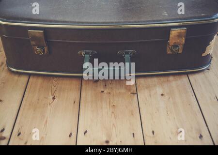 An old vintage brown travel suitcase on a wooden floor Stock Photo