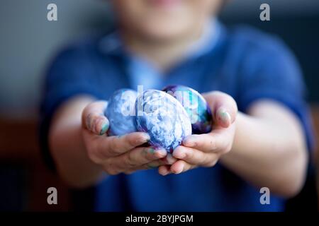 Sweet children, brothers, coloring and paiting eggs for Easter in garden, outdoors at home in backyard Stock Photo