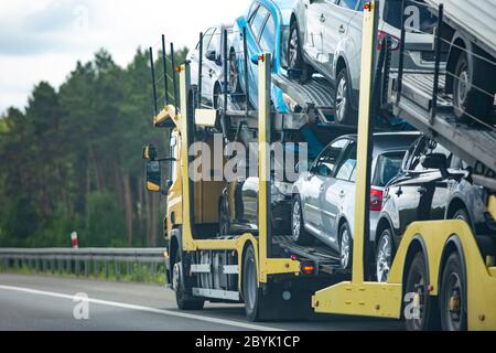 Car transporter trailer loaded with many cars on a highway, motion blur effect. Stock Photo