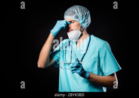 Photo of guy doc professional unhappy hold nose bridge tired after operation overwhelmed wear mask uniform suit gown plastic facial goggles surgical Stock Photo
