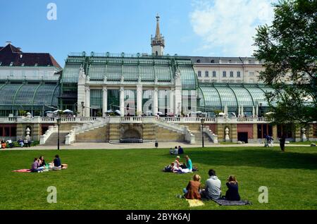 Vienna, Austria - April 24th 2011: unidentified people take a picnic in the grass of the public Burggarten with view to the new renovated palm house a Stock Photo