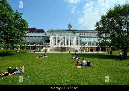 Vienna, Austria - April 24th 2011: unidentified people take a picnic in the grass of the public Burggarten with view to the new renovated palm house Stock Photo