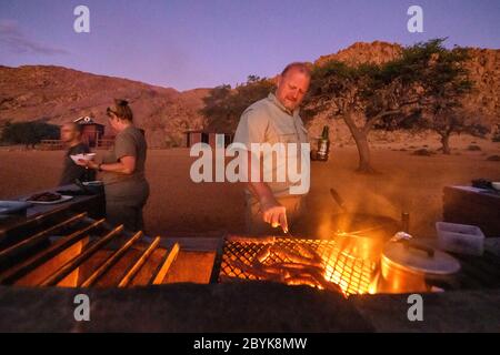 A member of the traveling party cooking up some food for everyone , Helmeringhausen, Namibia Stock Photo