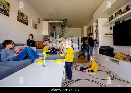 Many kids, doing different activities at home, reading book, playing with toys, eating, running, listening music, jumping Stock Photo