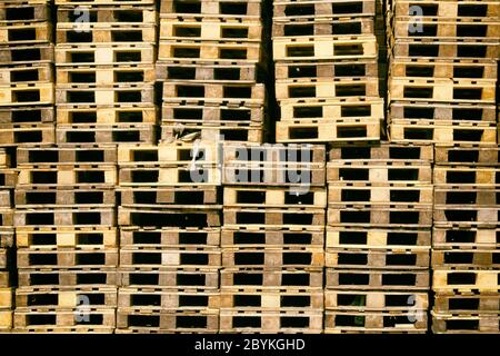 Pallets background. Stacks of brown rough wooden pallets at warehouse in industrial yard. Cargo and shipping concept.