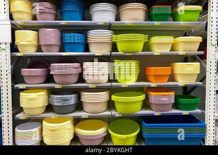 Shopping with background of colorful plastic baskets, bowls and basins on shelf. Inexpensive alternative to dishes made from natural materials. Stock Photo