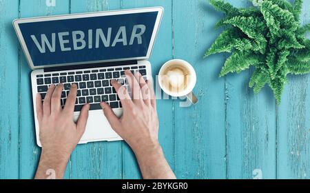 above view of person using laptop computer on wooden table to participate in webinar, online education and e-learning concept Stock Photo