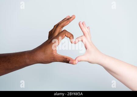Closeup photo of two arms different race skin color multiracial couple best friends antiracism issue concept help together showing heart figure love Stock Photo