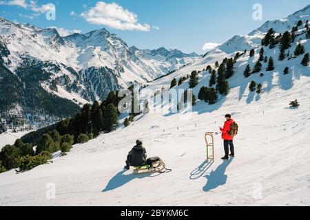 Speeding downhill on wooden sled. Happy influencer having fun with wood vintage sledding on snow high mountains - Natural sled runs Stock Photo