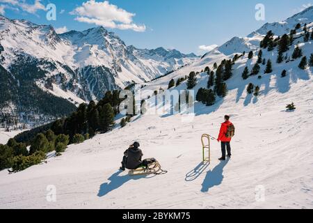 Speeding downhill on wooden sled. Happy influencer having fun with wood vintage sledding on snow high mountains - Natural sled runs Stock Photo
