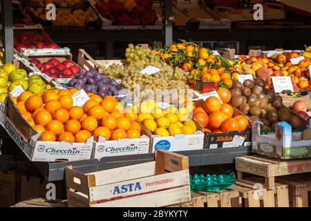 Brightly lit by sunshine fresh fruit in boxes and trays some with price tickets for sale at the Mercato Rialto in Venice, Italy Stock Photo
