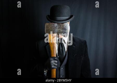Man in Dark Suit Holding Axe Over Face Stock Photo