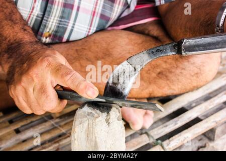 gardener rubber sharpening the knife with whetstone Stock Photo
