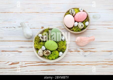 Easter decorations with eggs, moss and ceramic figurines on white wooden table. Festive time Stock Photo