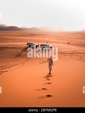 Off-road jeep going through incredible lunar landscape in Wadi Rum village in the Jordanian red sand desert. Wadi Rum also known as The Valley Stock Photo