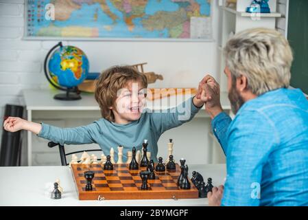 Young kid boy playing chess with father and having fun. Education and learning people concept - pupil and Teacher Stock Photo
