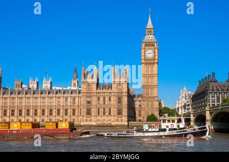 Cargo boat in front of Big Ben and the Houses of Parliament on the river Thames, London, UK Stock Photo