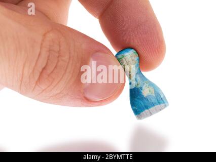 Hand holding wooden pawn, map painting, selective focus Stock Photo