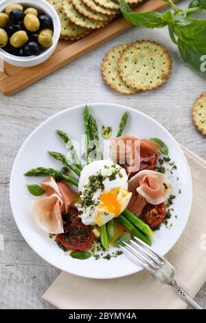 Best Eggs Benedict - Poached eggs with prosciutto, asparagus, sun-dried tomatoes and pesto Stock Photo