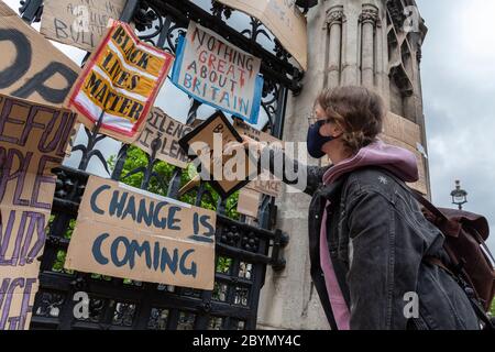 A protester places a sign on the fence of the Palace of Westminster after a Black Lives Matters protest, Parliament Square, London, 7 June 2020 Stock Photo