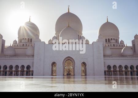 Abu Dhabi / United Arab Emirates - February 5, 2020: sun star behind dome of Sheikh Zayed Grand Mosque during sunset Stock Photo