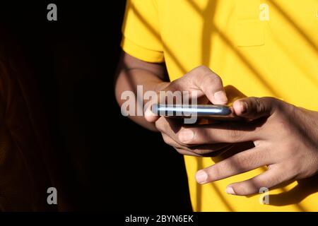 young man in yellow shirt using smart phone  Stock Photo