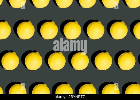 Repeating seamless photo pattern of fresh whole lemons on dark graphite color background. Vivid black and yellow texture. Stock Photo