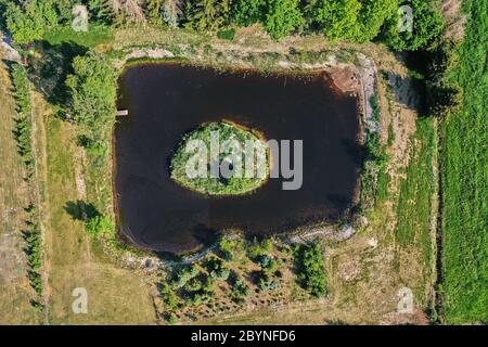Abstract vertical aerial view of a small pond with a tiny round island. Stock Photo