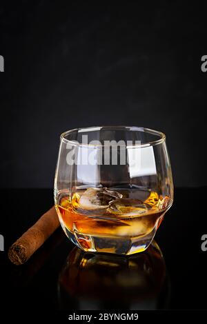 Glass of whiskey and cigar on dark background. Stock Photo