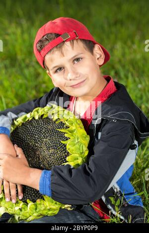 Young happy boy hold sunflower in a garden Stock Photo