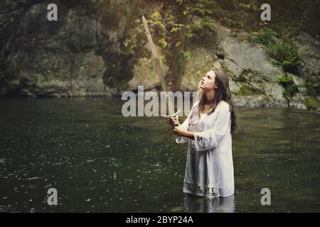 Beautiful woman with a sword in a stream . Fantasy and legend conceptual Stock Photo