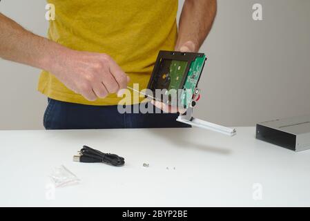 IT Technician fitting hard disk drive into external enclosure Stock Photo