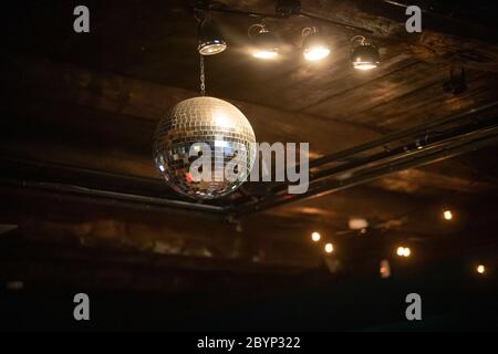 Closeup of mini disco balls under red and orange lights with a