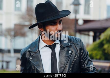 A bearded Indian man in a black hat walks down the street. Stock Photo