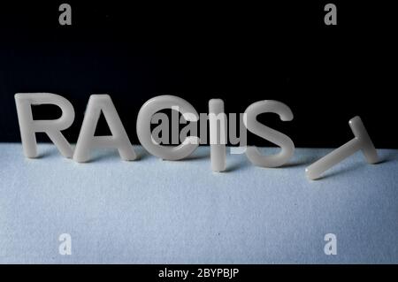 Drop racist, word written with letters on a two-tone background, the last letter fell. Concept against racism. Stock Photo
