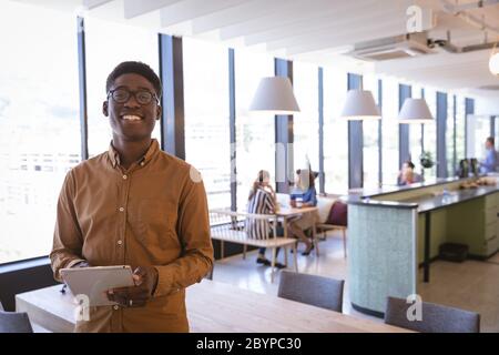 Young Man Using Tablet In workshop, African American man employee works with sewing machine ...